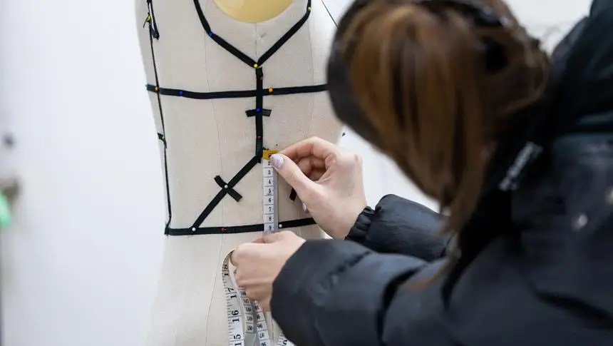 a person measuring a mannequin