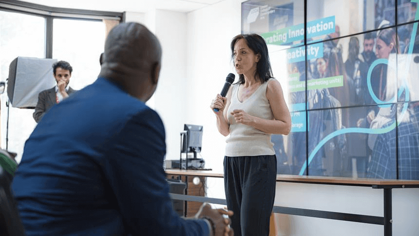 a women talking with a mic in her hand with a presentation