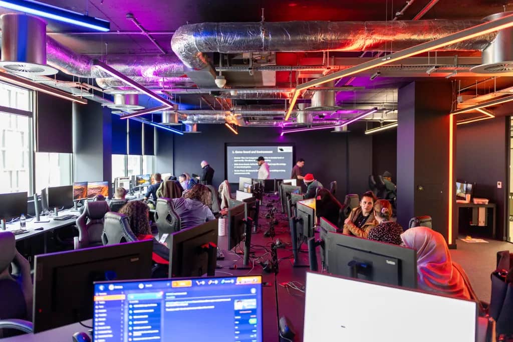 Students in a gaming lab with colourful lights and gaming softwares on screen