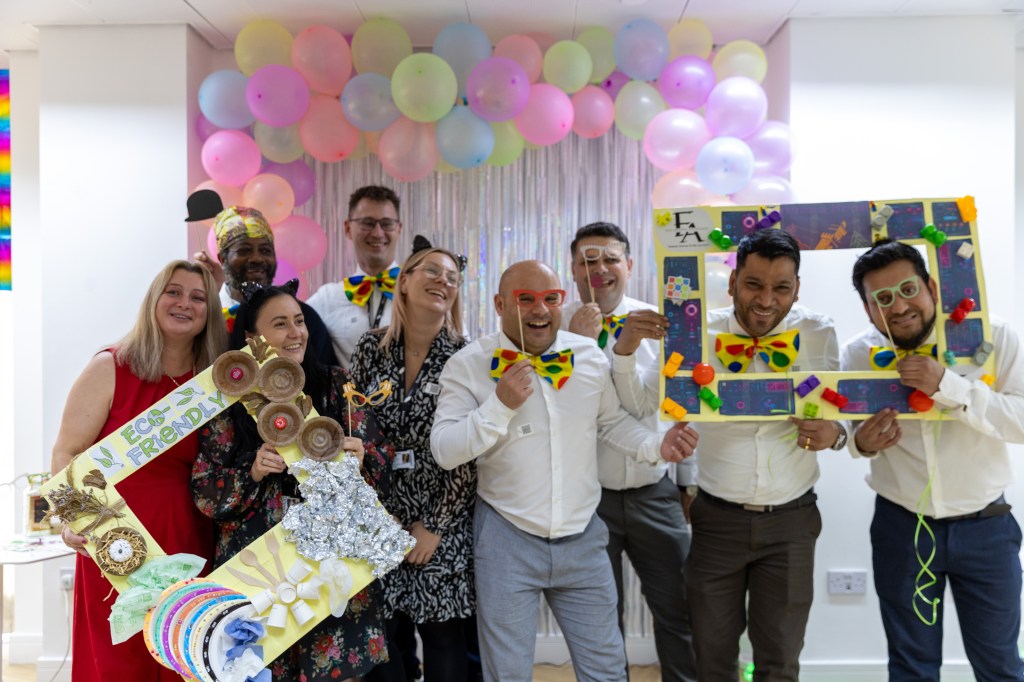 Hospitality students taking a group photo laughing together with props like photo frame and balloons