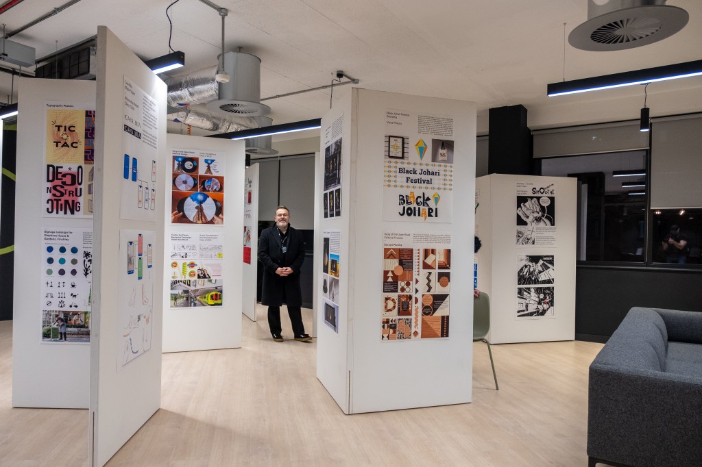 Student standing in a graphic design artwork exhibition