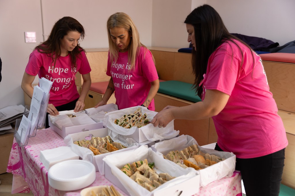 Hospitality students serving food at an event in pink shirts