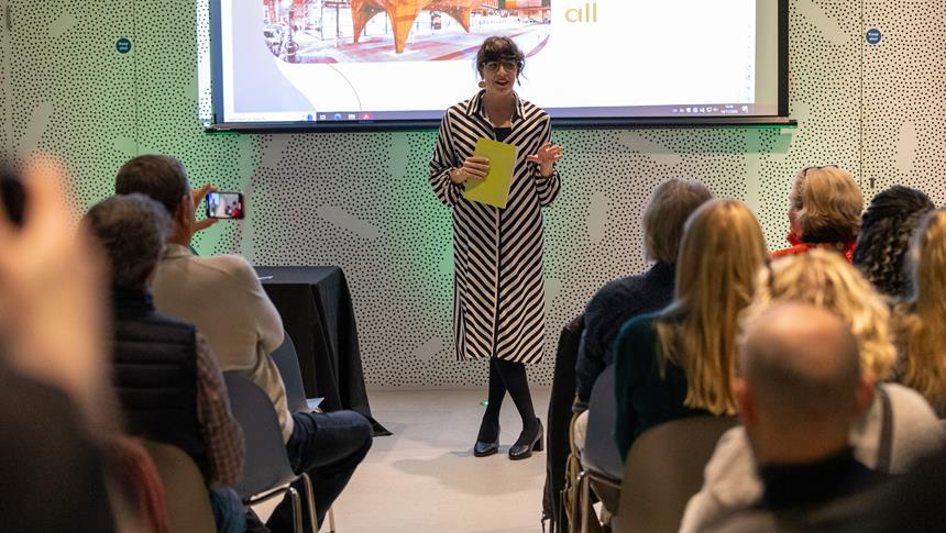 Woman presenting to a class holding a notepad
