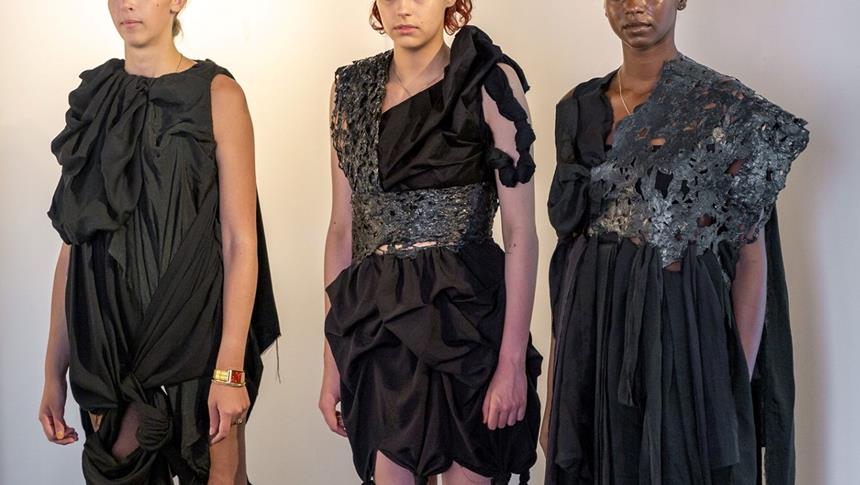 3 models wearing black clothes posing at an exhibition