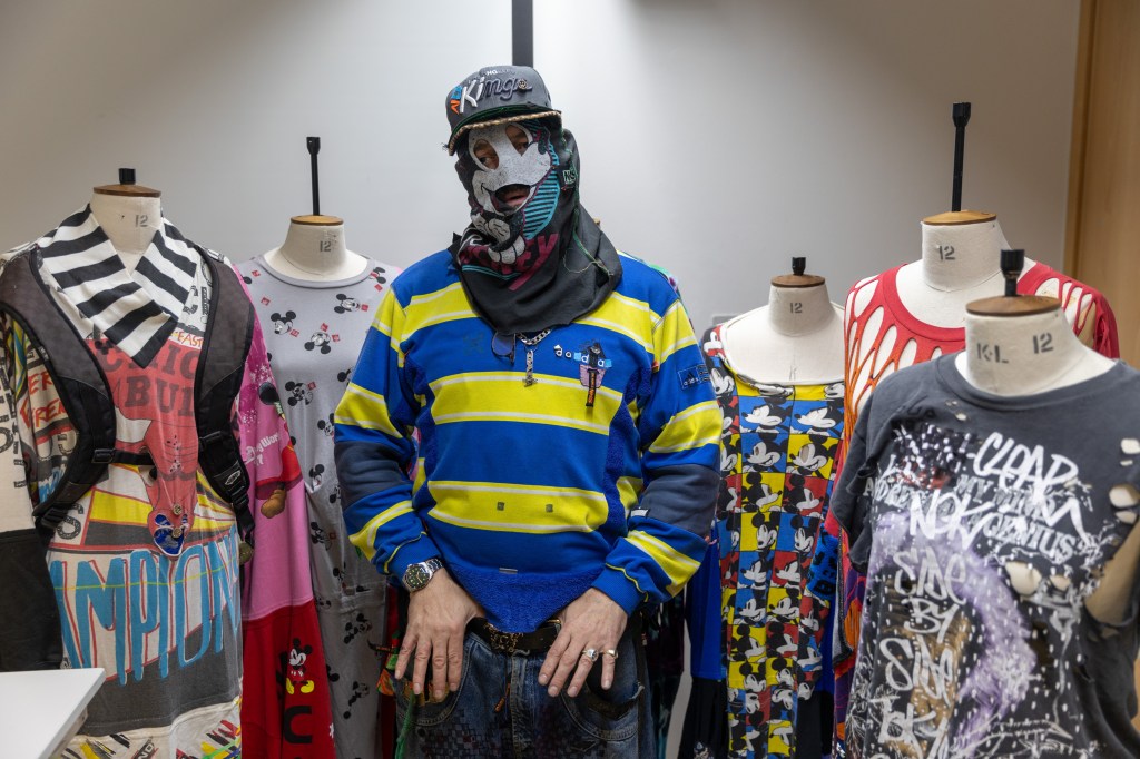 a student in a mask standing with mannequins