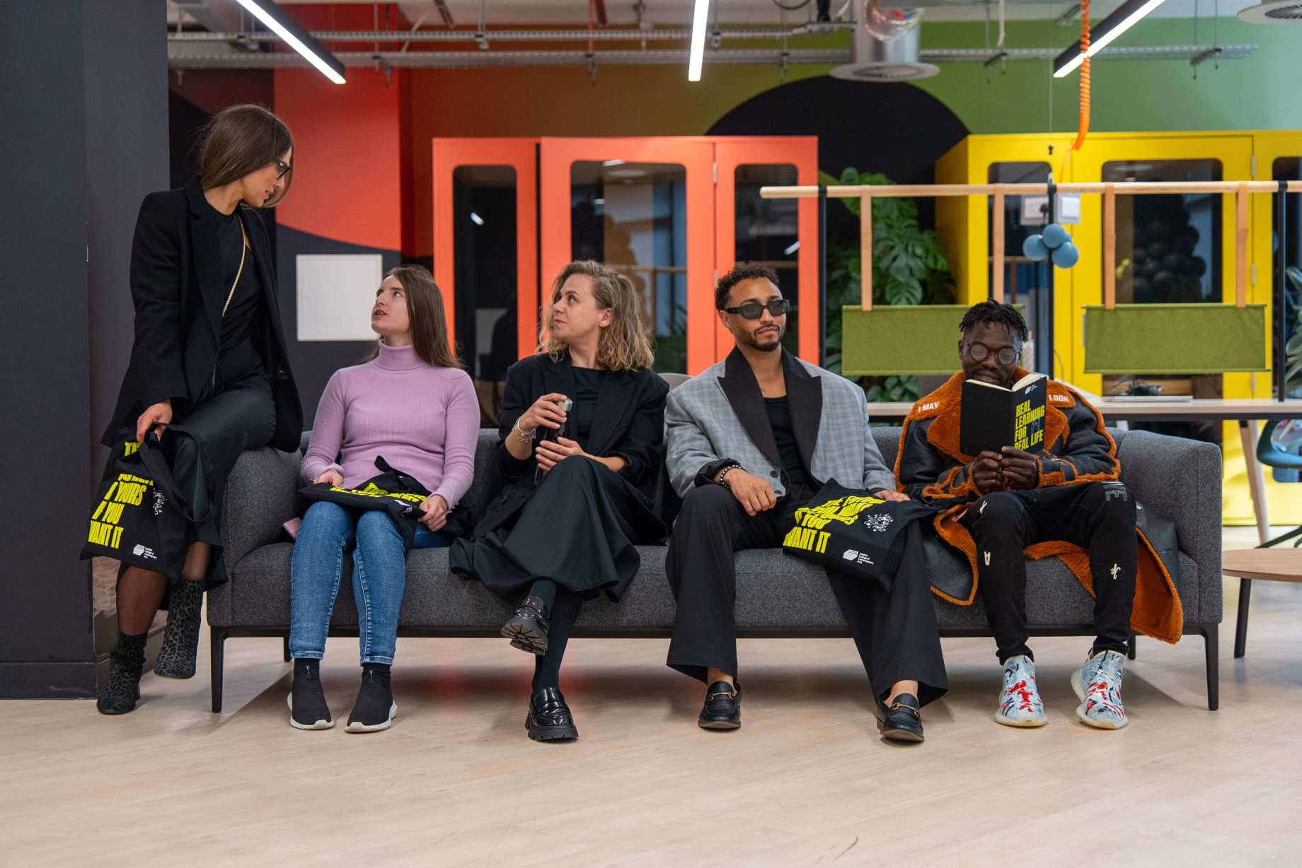 5 people sitting on a sofa talking to each other