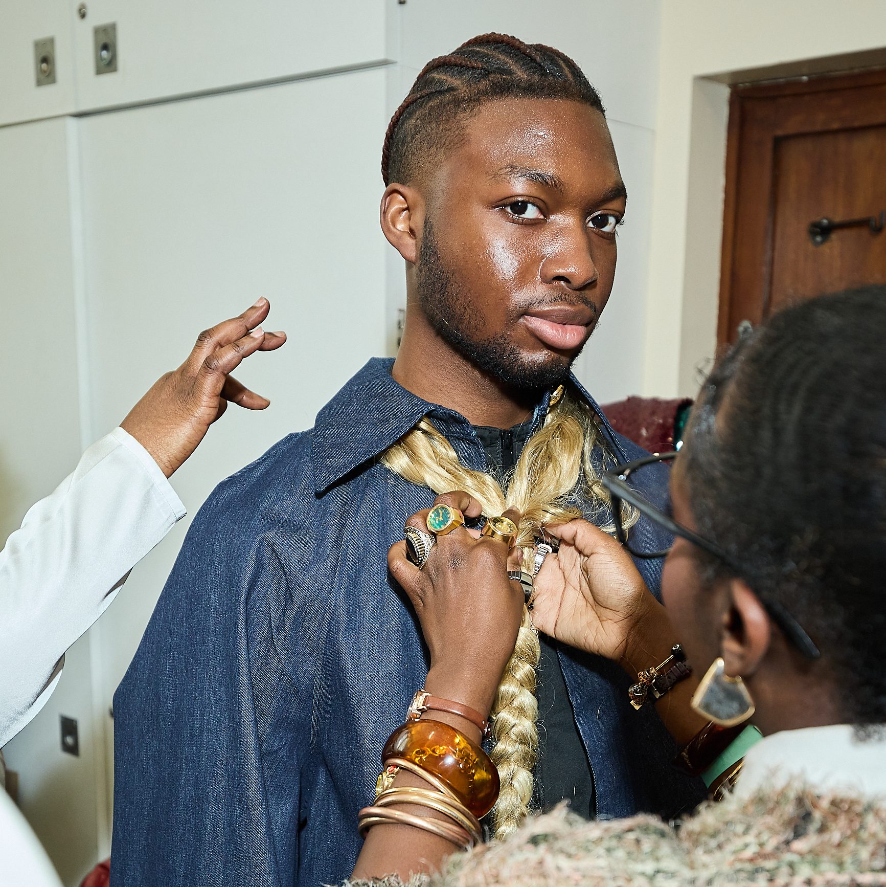 Male model in a behind the scenes shot of a fashion show being fitted for the runway