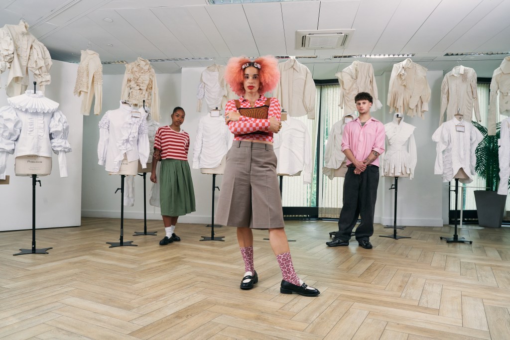 3 people posing by an exhibition put up fashion students