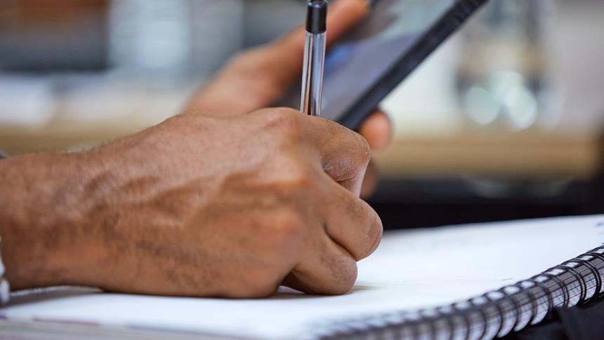 a hand writing with a pen on a notepad
