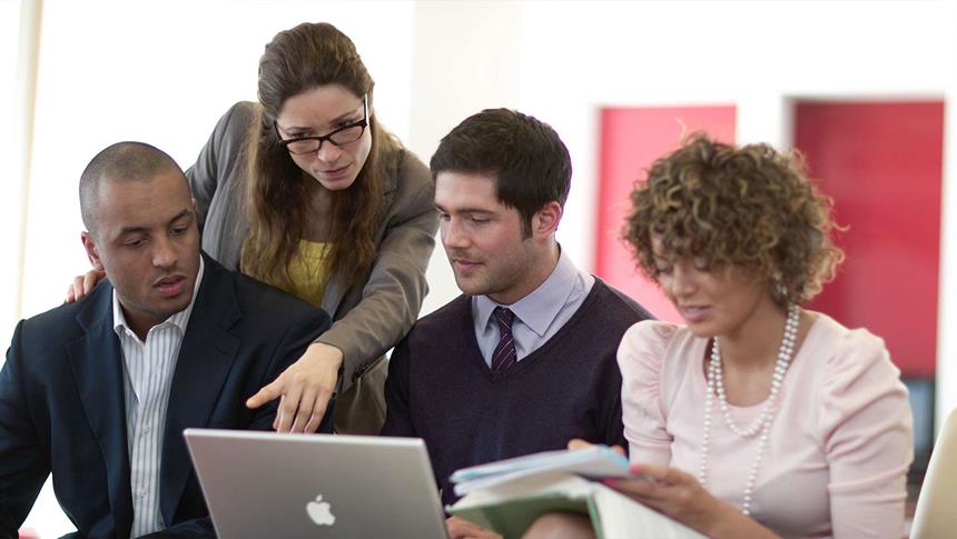 4 people talking to each other looking at a laptop