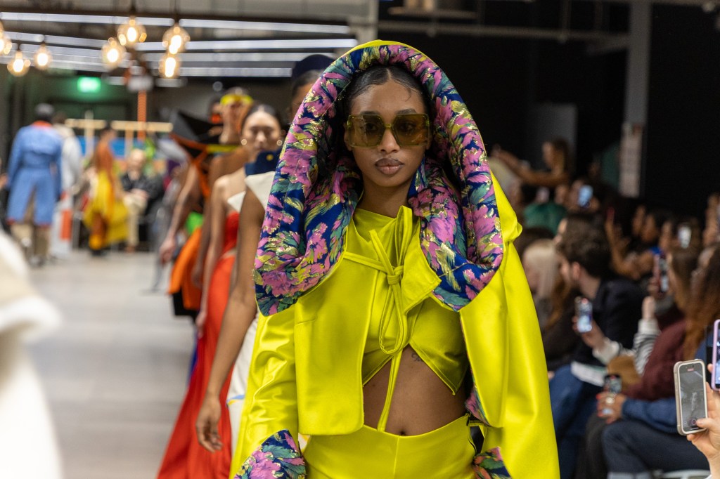 Catwalk of a Fashion Runway. Woman in Yellow outfit and sunglasses.