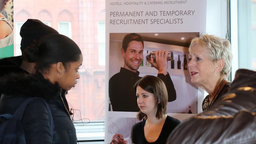 2 people talking to students at a careers fair